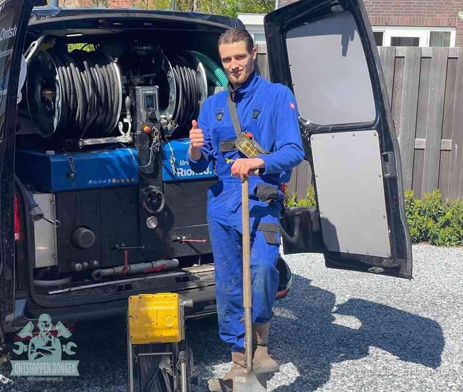 Een monteur bij de werkbus met grote hogedruk-slanghaspels, apparatuur voor hardnekkige afvoerverstoppingen in Dongen