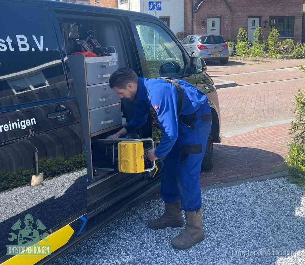 Een monteur pakt buiten op de oprit gereedschap uit de bedrijfsbus, het moment om een professional in te schakelen voor een verstopte afvoer in Dongen