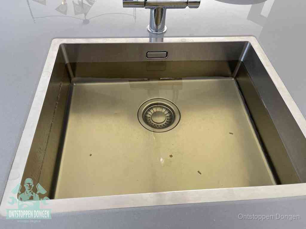 Stilstaand water in een rvs spoelbak dat niet wegloopt, een duidelijk signaal van een gootsteenverstopping in Dongen