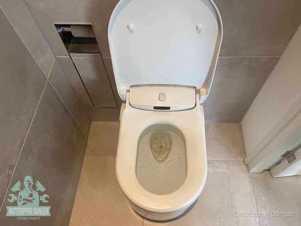 Een wit hangtoilet waarin een prop wc-papier op het water blijft drijven, een duidelijk signaal van een verstopte wc in Dongen