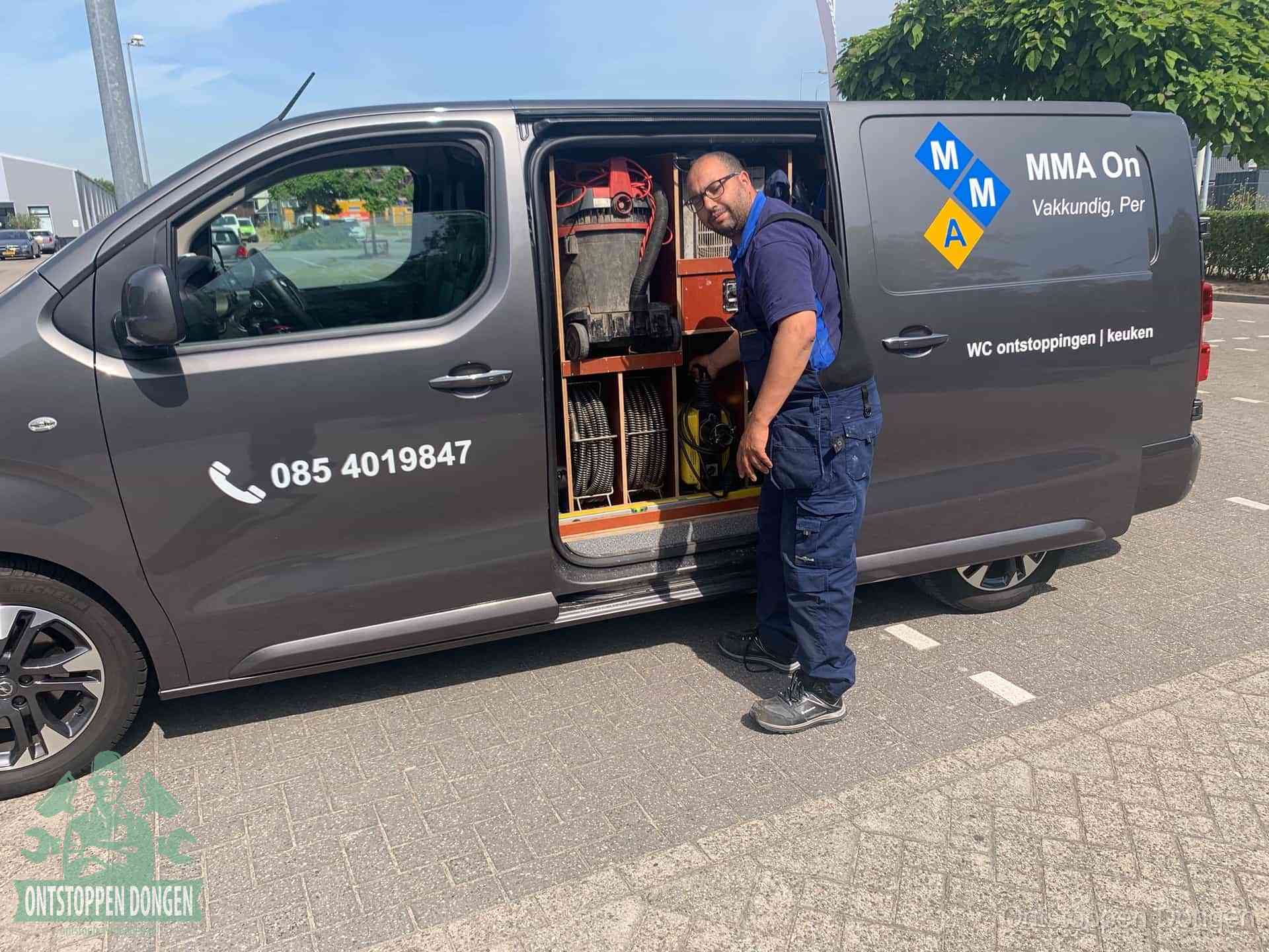 Een monteur bij de open schuifdeur van zijn bedrijfsbus op een parkeerplaats, klaar om de oorzaak van terugkerende afvoerverstoppingen aan te pakken in Dongen