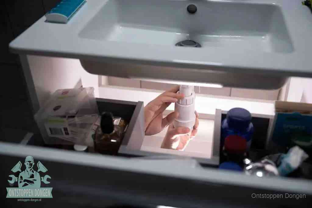 Een pompfles met zeep boven een wastafel in de toiletruimte, de warm water en afwasmiddel-methode om de wc te ontstoppen in Dongen