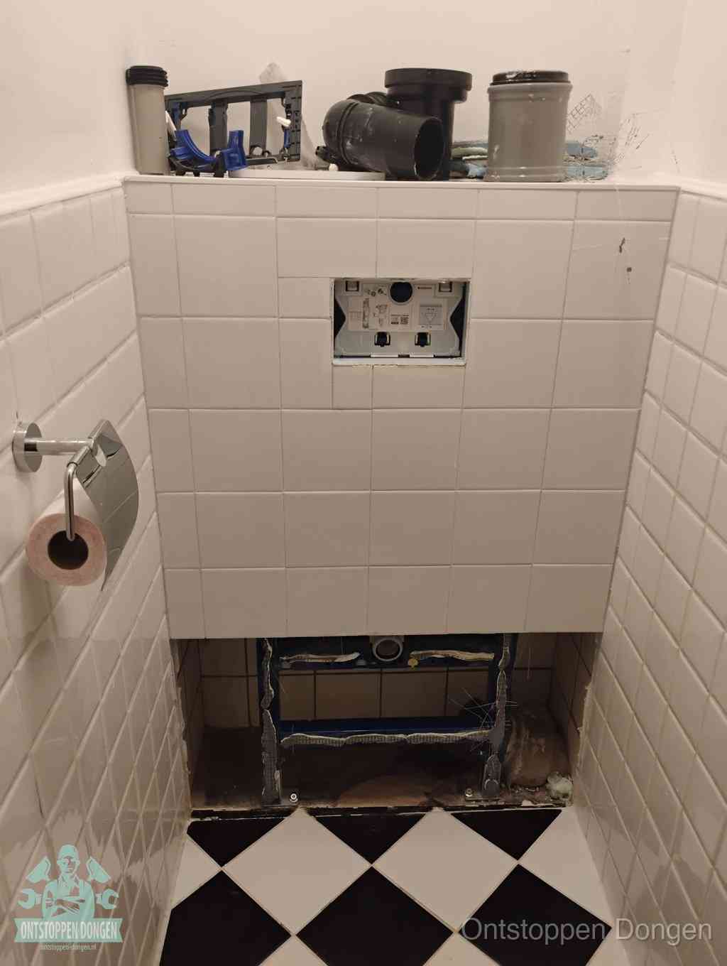 Een toiletruimte waar het hangtoilet en de inbouwreservoir-onderdelen zijn vrijgelegd voor onderhoud, periodiek nazicht voorkomt een wc-verstopping in Dongen